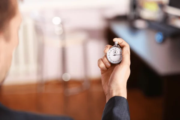 Geschäftsmann hält Stoppuhr in der Hand – Fokus auf Zeiterfassung für Selbständige im Büro