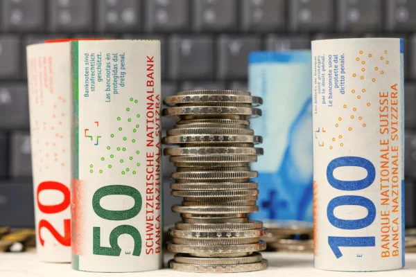 Schweizer Franken Banknoten und Münzen gestapelt vor Computertastatur – Symbol für Kassenbuchführung